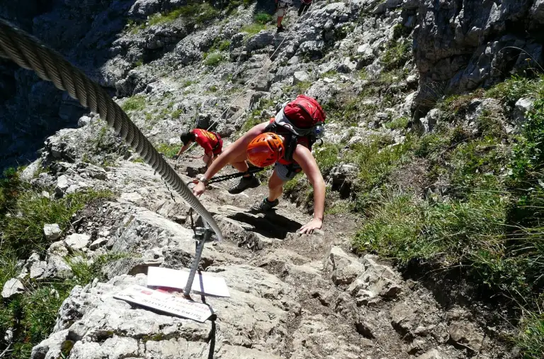 Une personne en train d'escalader la montagne lors de la via ferrata